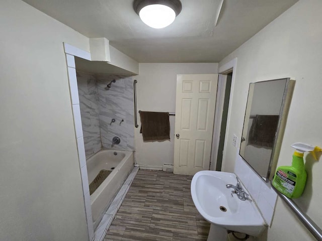 bathroom with hardwood / wood-style flooring, sink, and tiled shower / bath