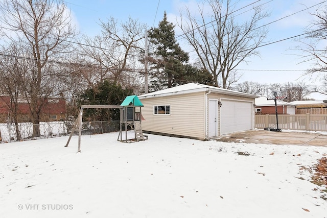 snowy yard featuring an outbuilding and a garage