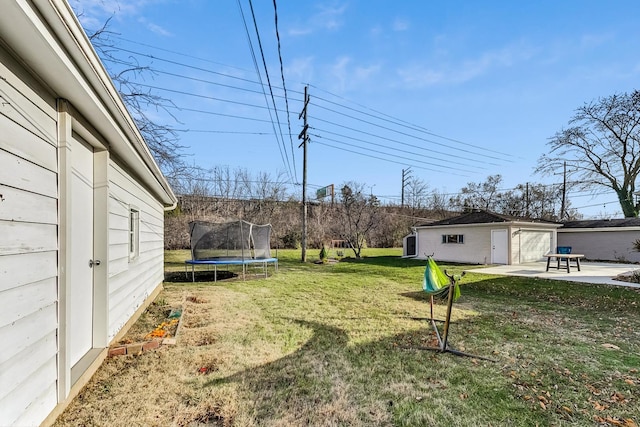 view of yard featuring a garage, an outbuilding, and a patio area