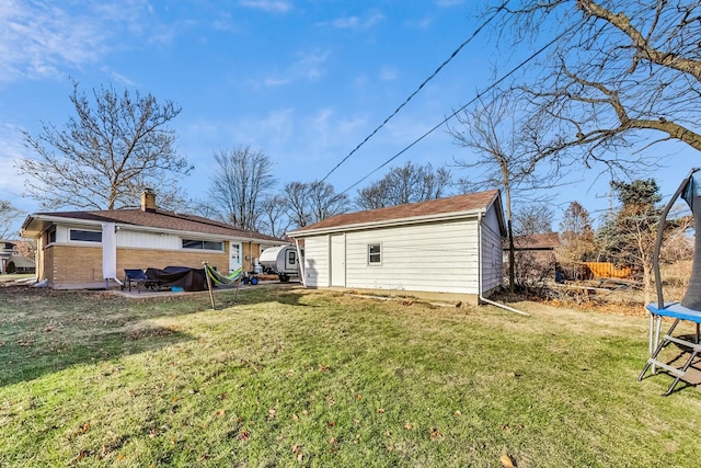 back of house featuring a storage unit, a trampoline, and a yard