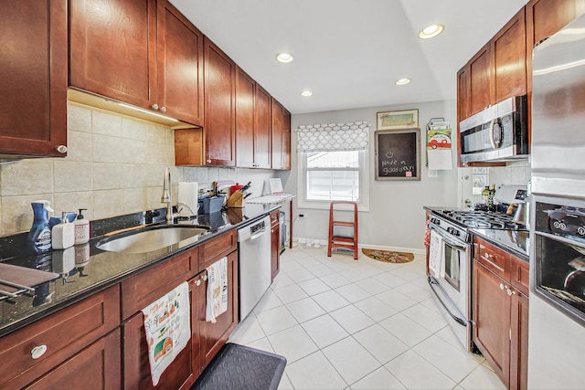 kitchen with sink, stainless steel appliances, dark stone counters, decorative backsplash, and light tile patterned flooring