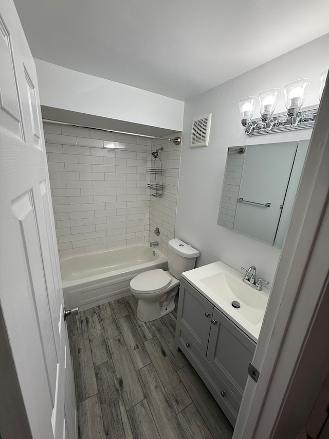 full bathroom featuring hardwood / wood-style flooring, vanity, toilet, and tiled shower / bath combo