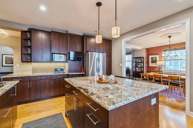 kitchen with light wood finished floors, open shelves, built in microwave, and freestanding refrigerator