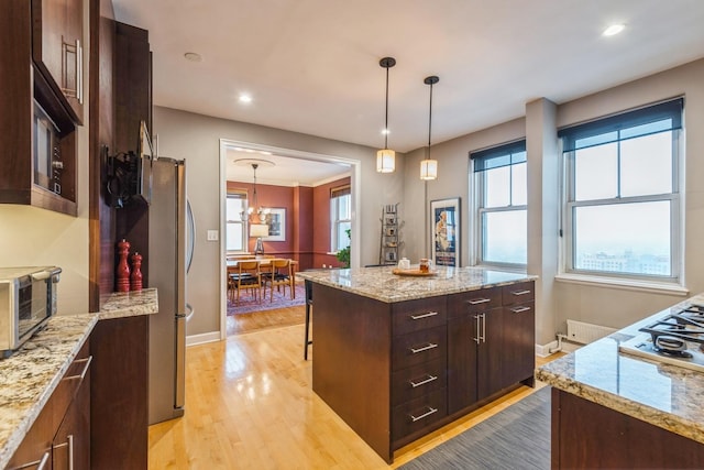 kitchen with a chandelier, stainless steel appliances, light wood-style floors, hanging light fixtures, and a center island