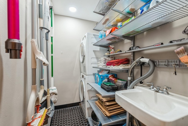 washroom with stacked washer and dryer, baseboards, laundry area, and a sink