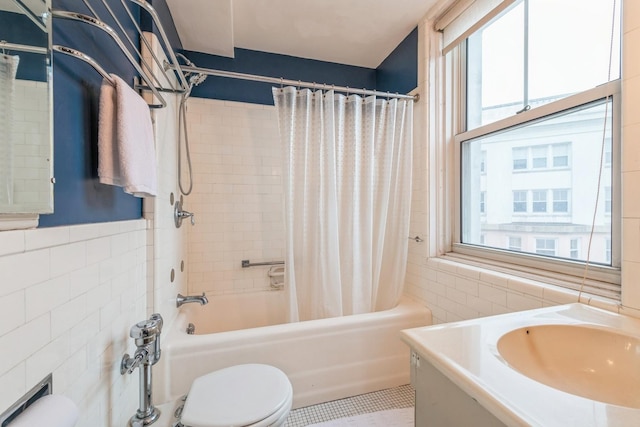 bathroom with toilet, a sink, shower / bathtub combination with curtain, wainscoting, and tile walls