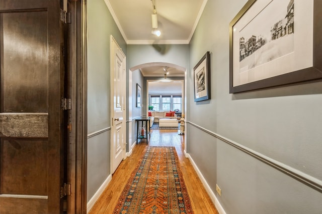 corridor with hardwood / wood-style floors, crown molding, and track lighting