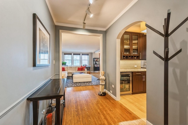 corridor with crown molding, wine cooler, and light wood finished floors
