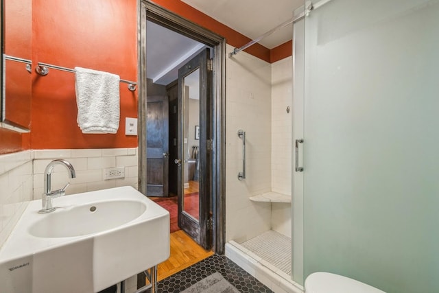 full bath featuring tile walls, a sink, a stall shower, and toilet