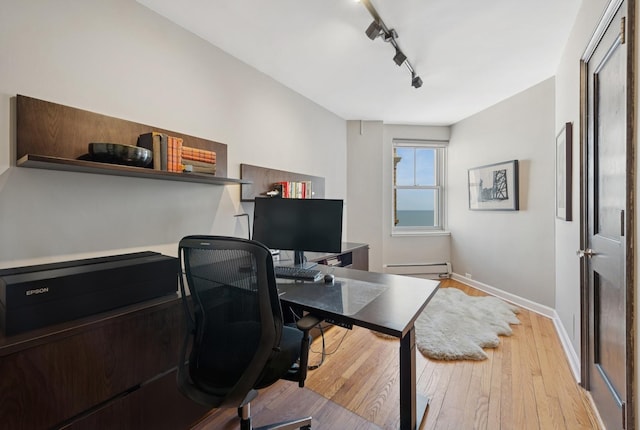 home office featuring wood-type flooring, track lighting, baseboards, and a baseboard heating unit