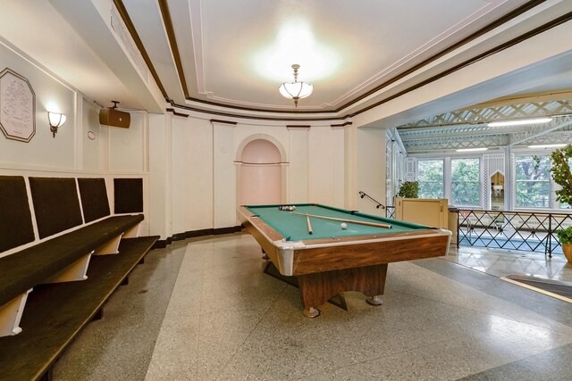 recreation room with crown molding, pool table, a raised ceiling, a decorative wall, and baseboards