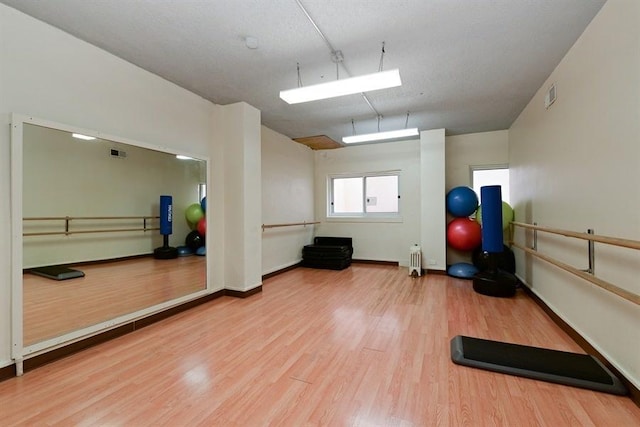 exercise area featuring baseboards, visible vents, and wood finished floors