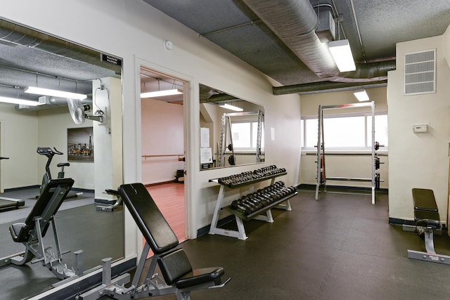 gym with a textured ceiling, baseboards, and visible vents