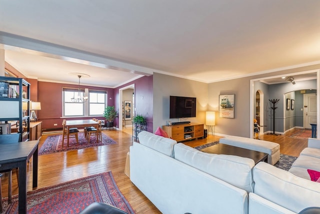 living room with arched walkways, ornamental molding, light wood-style flooring, and a notable chandelier