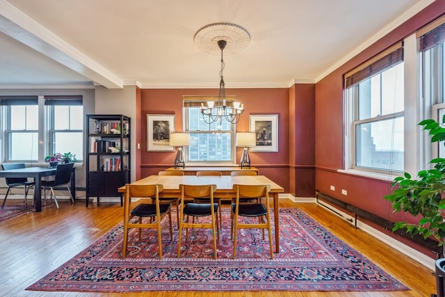 dining room featuring crown molding, baseboards, wood finished floors, a baseboard heating unit, and a notable chandelier