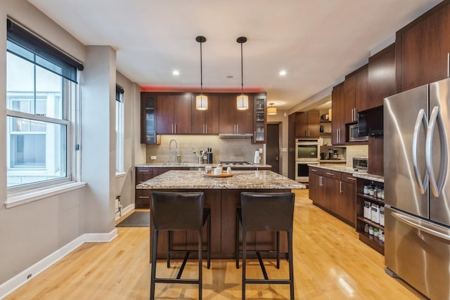 kitchen featuring glass insert cabinets, a sink, backsplash, and appliances with stainless steel finishes