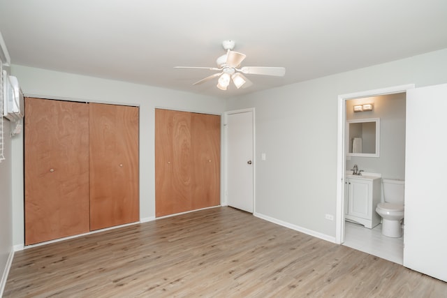 unfurnished bedroom with multiple closets, ceiling fan, sink, ensuite bathroom, and light hardwood / wood-style floors