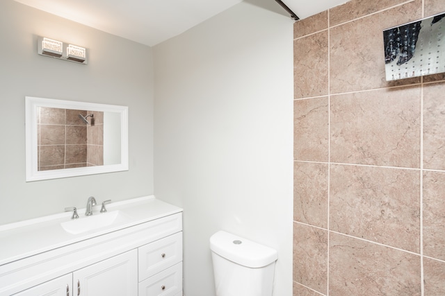 bathroom with a tile shower, vanity, and toilet