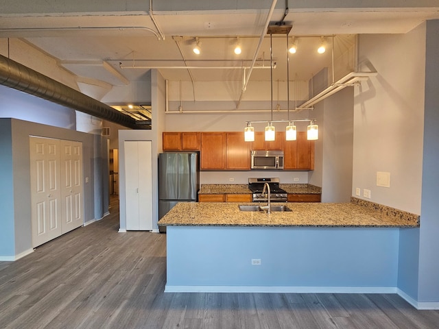 kitchen with sink, stainless steel appliances, dark hardwood / wood-style floors, kitchen peninsula, and pendant lighting