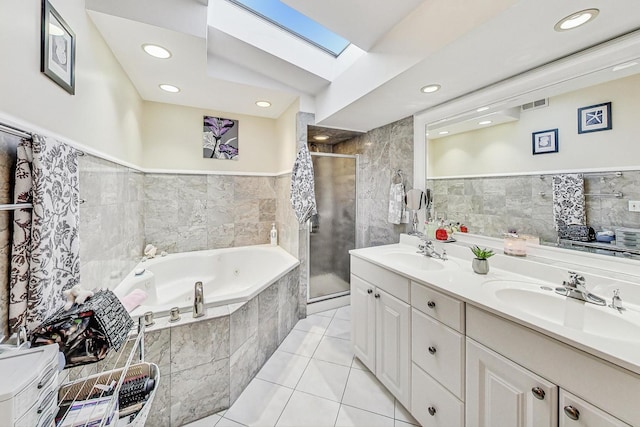 bathroom featuring a skylight, tile patterned flooring, vanity, and independent shower and bath