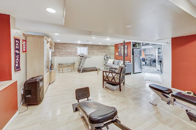 interior space featuring independent washer and dryer, light hardwood / wood-style flooring, and brick wall