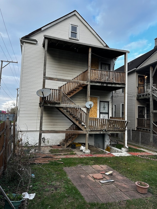 back of property with a lawn and a balcony