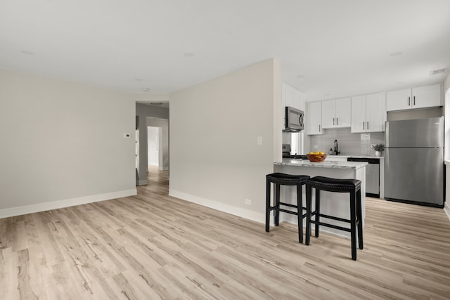 kitchen with sink, stainless steel appliances, white cabinetry, and light hardwood / wood-style flooring