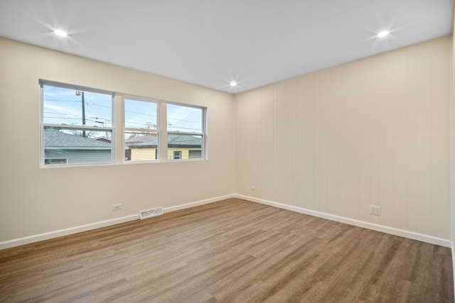 spare room featuring hardwood / wood-style flooring and wooden walls