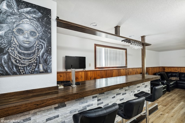 interior space featuring wood walls, light hardwood / wood-style floors, and a textured ceiling