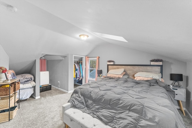 bedroom featuring carpet floors, a spacious closet, a closet, and vaulted ceiling with skylight