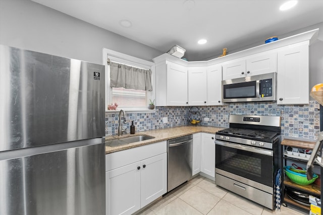 kitchen featuring decorative backsplash, appliances with stainless steel finishes, light stone countertops, sink, and white cabinets