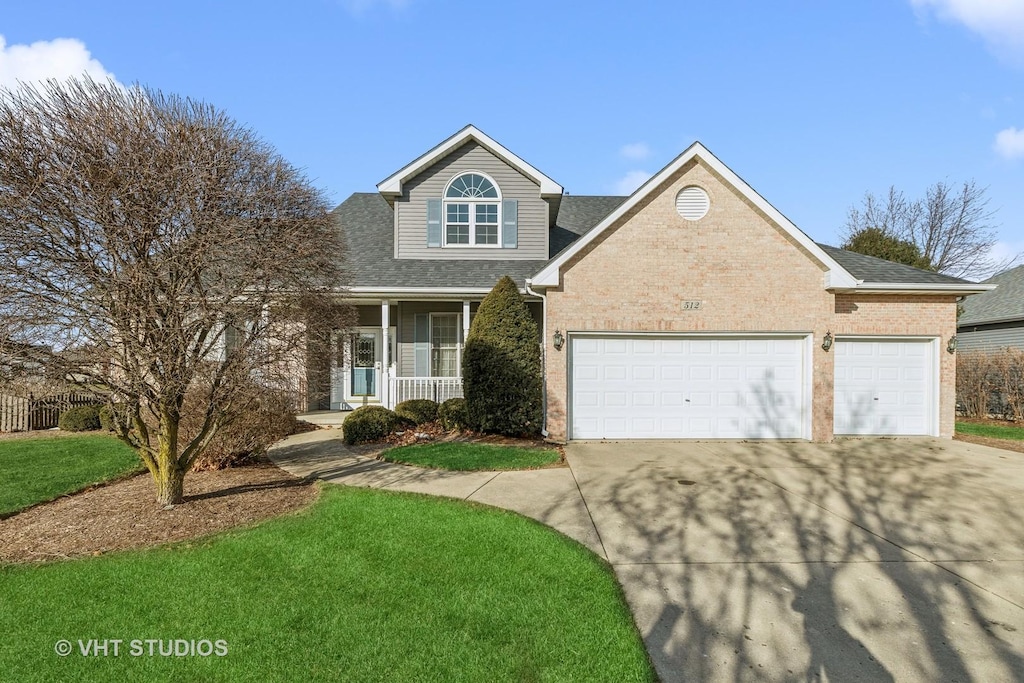 view of front of home featuring a garage, covered porch, and a front yard