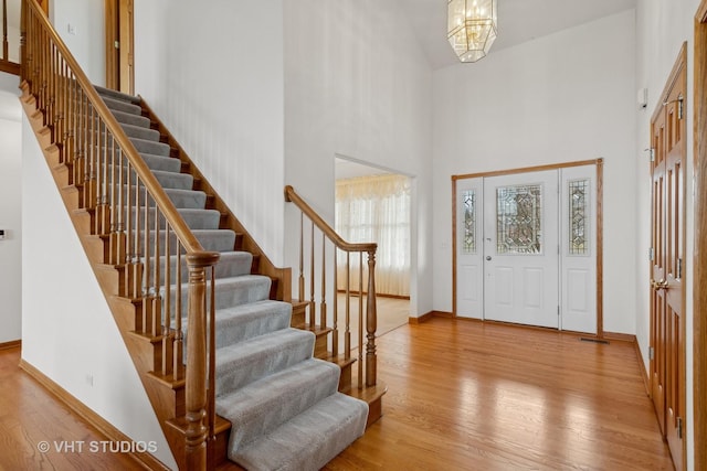 foyer with an inviting chandelier, a high ceiling, and light wood-type flooring