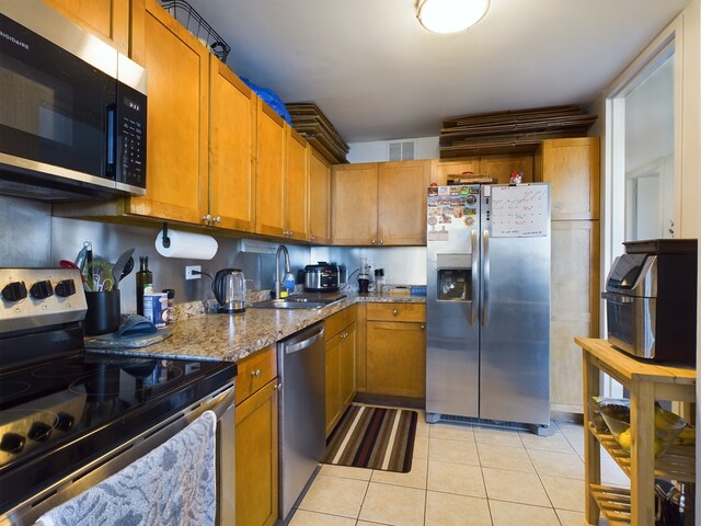 655 W Irving Park Rd Unit 1710, Chicago, IL 60613 - kitchen with appliances with stainless steel finishes, light tile patterned floors, brown cabinets, light stone countertops, and a sink