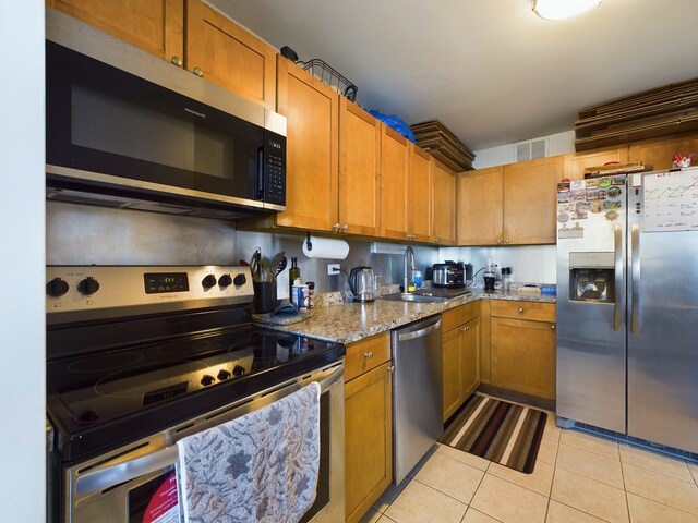 655 W Irving Park Rd Unit 1710, Chicago, IL 60613 - kitchen with appliances with stainless steel finishes, a sink, light tile patterned floors, light stone counters, and brown cabinetry