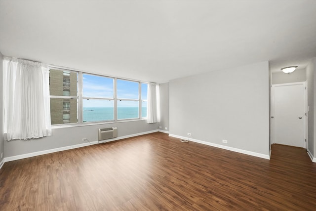 unfurnished room with a wall mounted air conditioner, dark hardwood / wood-style floors, and a water view