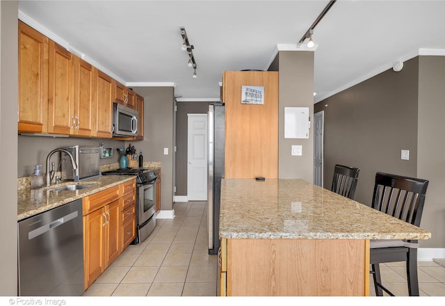 kitchen with rail lighting, a breakfast bar, light stone countertops, and stainless steel appliances