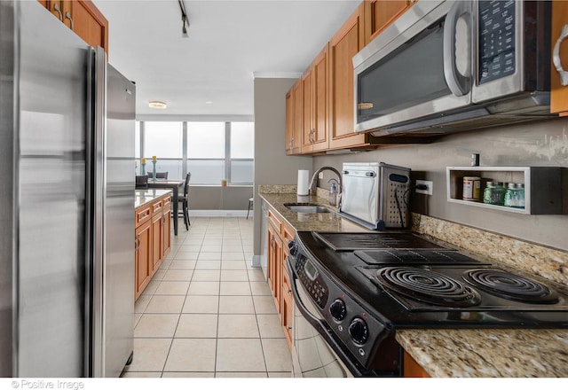 kitchen featuring sink, light stone countertops, stainless steel appliances, and light tile patterned floors