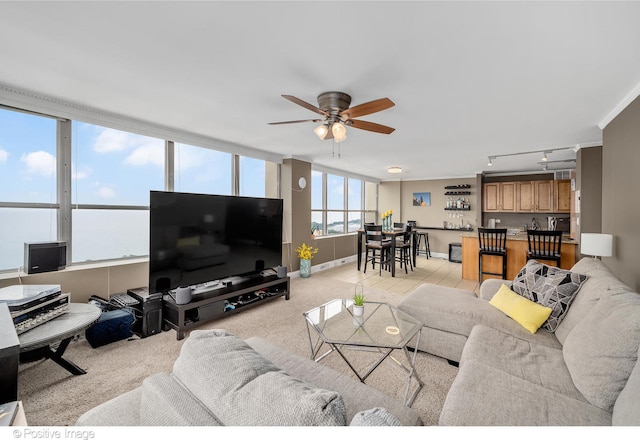 carpeted living room with track lighting, ceiling fan, and crown molding