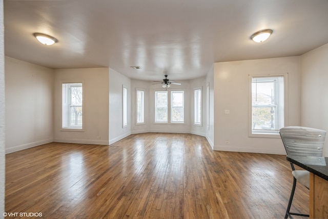 unfurnished living room featuring ceiling fan, dark wood-type flooring, and a healthy amount of sunlight