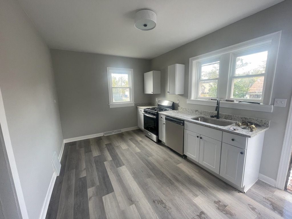 kitchen featuring white cabinets, appliances with stainless steel finishes, plenty of natural light, and sink