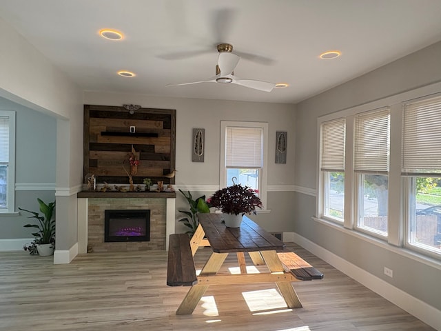 dining area with ceiling fan, a fireplace, built in features, and light hardwood / wood-style flooring