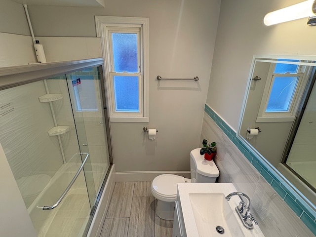 bathroom with a shower with door, vanity, and toilet