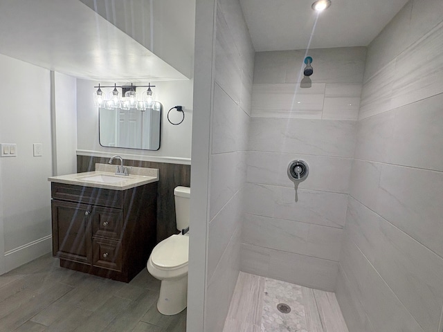 bathroom featuring a tile shower, vanity, and toilet