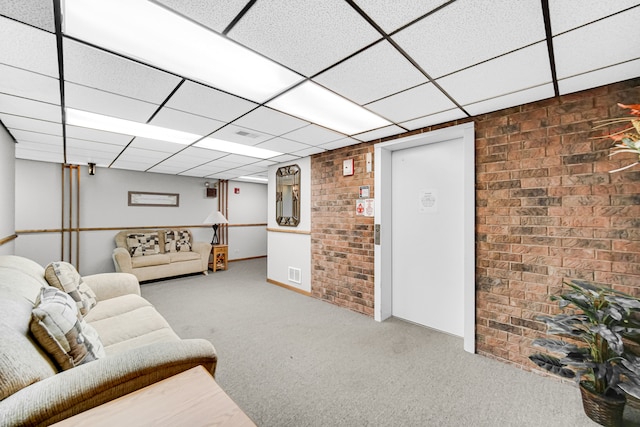 living room with carpet floors, a drop ceiling, and brick wall