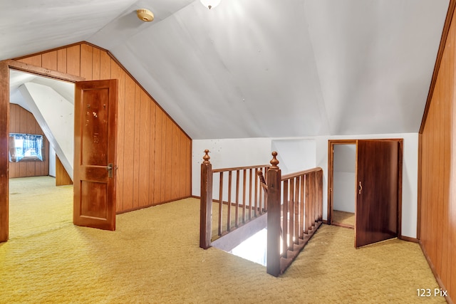 bonus room featuring wooden walls, light carpet, and vaulted ceiling