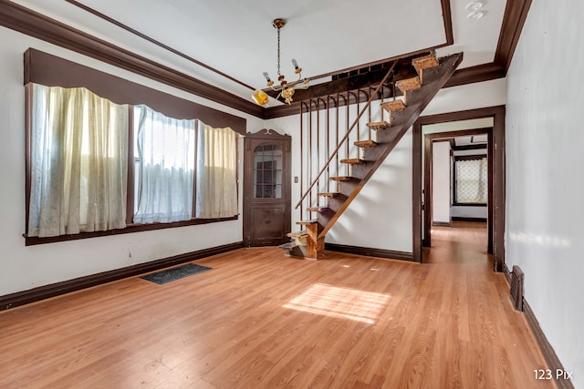 empty room with a chandelier, wood-type flooring, and ornamental molding