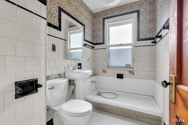 bathroom featuring tile patterned floors, toilet, tile walls, and a tub