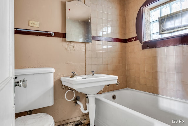 bathroom with a tub to relax in and toilet