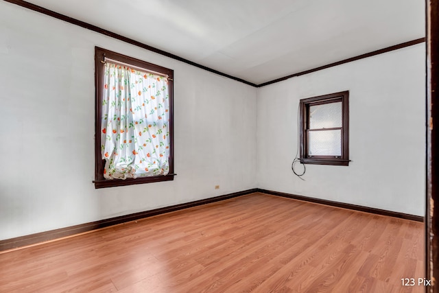 empty room featuring light hardwood / wood-style floors, ornamental molding, and a wealth of natural light